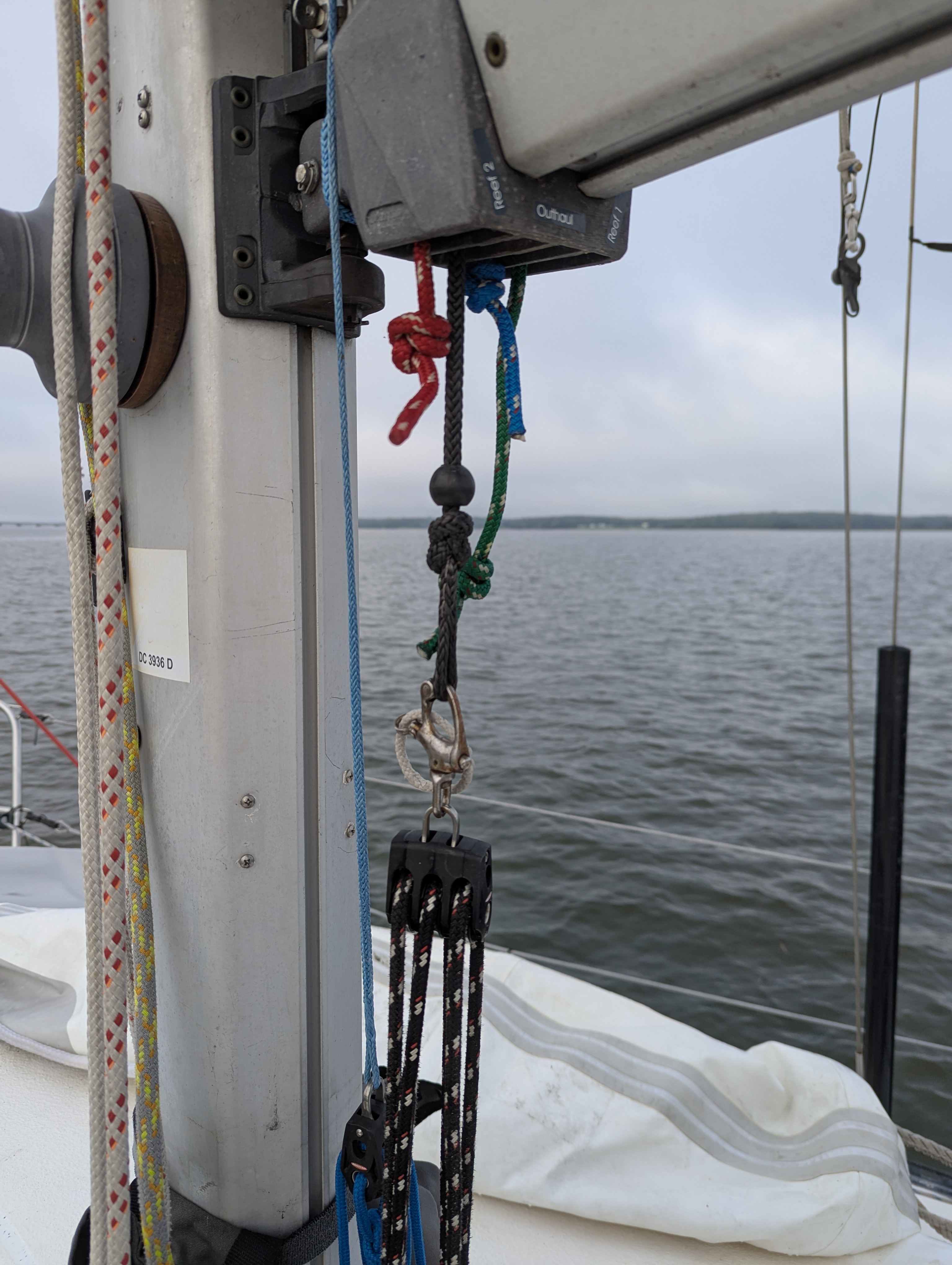 Ronstan triple block with attached snap shackle, attached to gray dyneema loop running from bottom of boom.