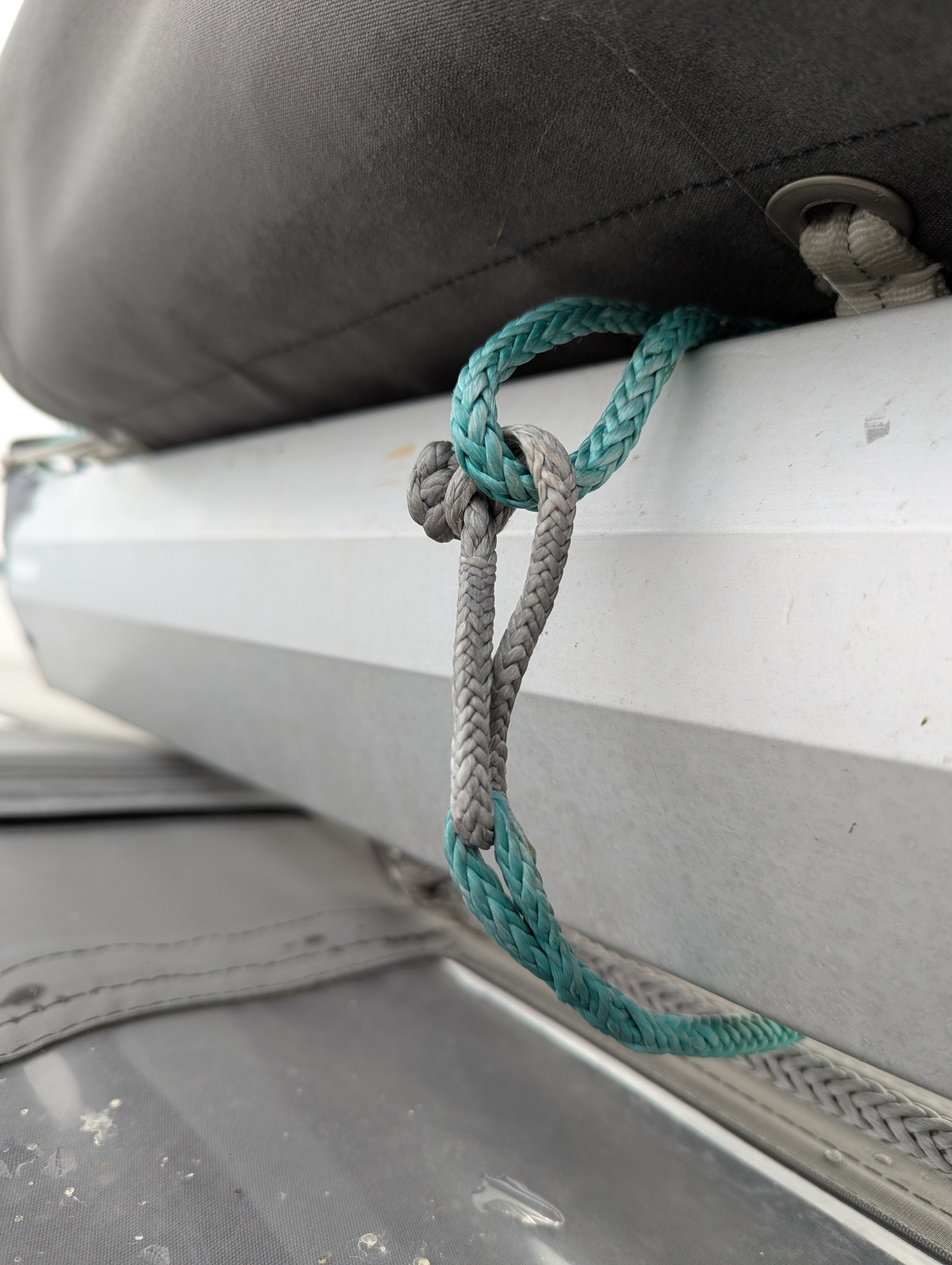 Closeup view of a single reef line around the boom; a soft shackle is looped through a spliced eye and around the line to form a larger loop.